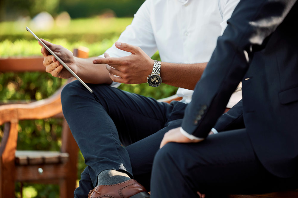 Two men in business wear pointing at an ipad screen