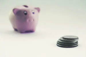 Tristan Hartey 3 A small pink piggy bank positioned next to a pile of coins